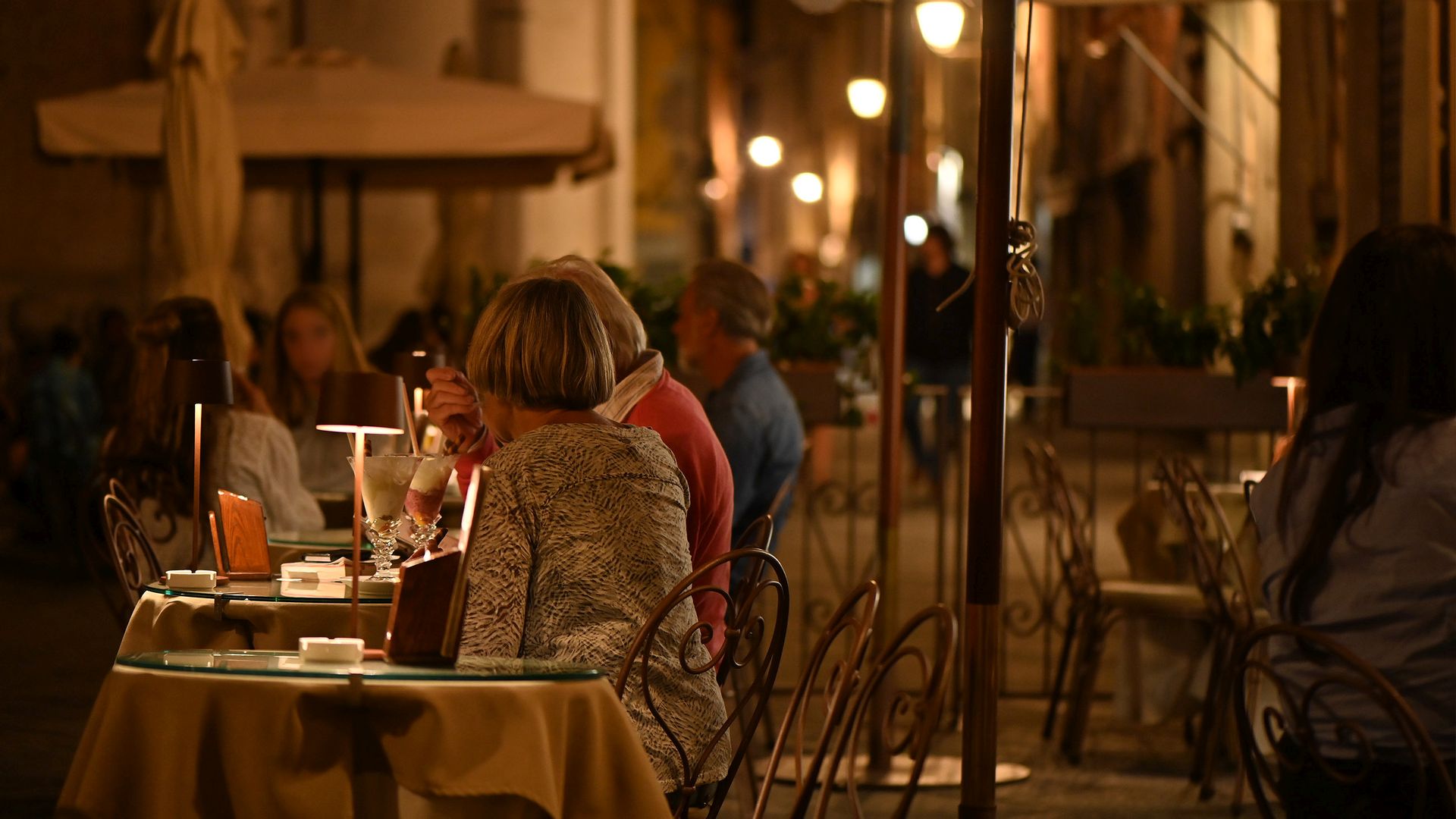 Deux femmes sont assises à la table d'un bar dans le centre historique de Lucques, le soir.